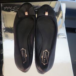 These Ted Baker London ballet flats are black with a decorative bow detail on the toe. They are made of leather and feature a patterned interior. UK s