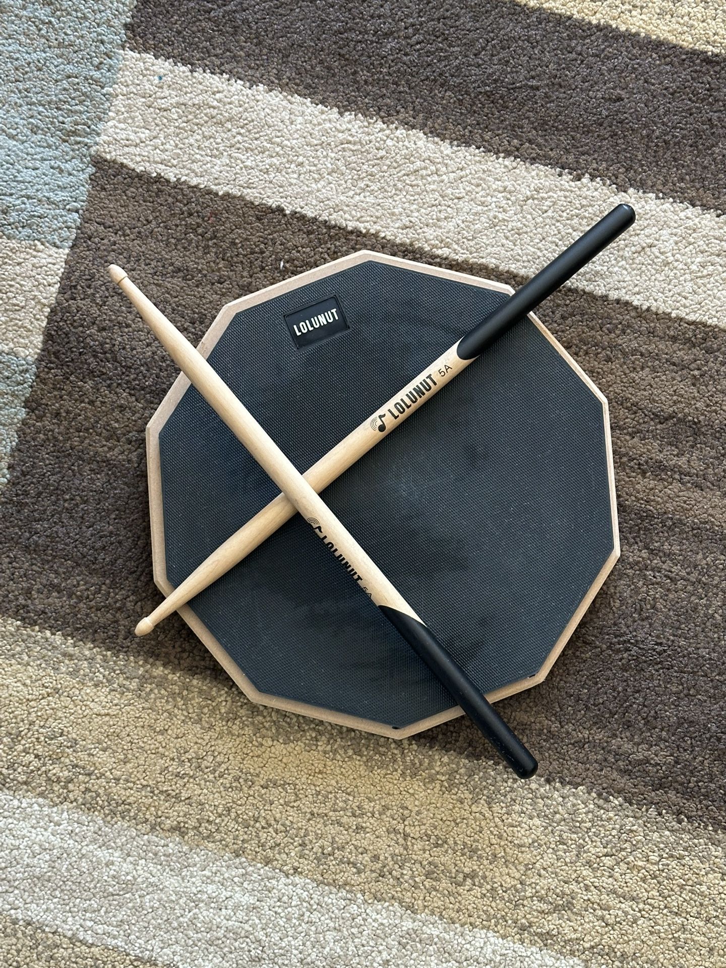 LOLUNUT drum practice pad with drumsticks.
