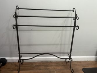 Sturdy decorative black metal rack — perfect for holding blankets, quilts, or even towels. 	•	3 horizontal bars for storage 	•	Scroll design on sides 
