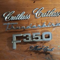 VINTAGE AUTO EMBLEMS,  THUNDERBIRD,  CUTLASS, MONTE, F350, AND FAIRLANE 500. ALL IN GOOD CONDITION,  NEEDS CLEANING 