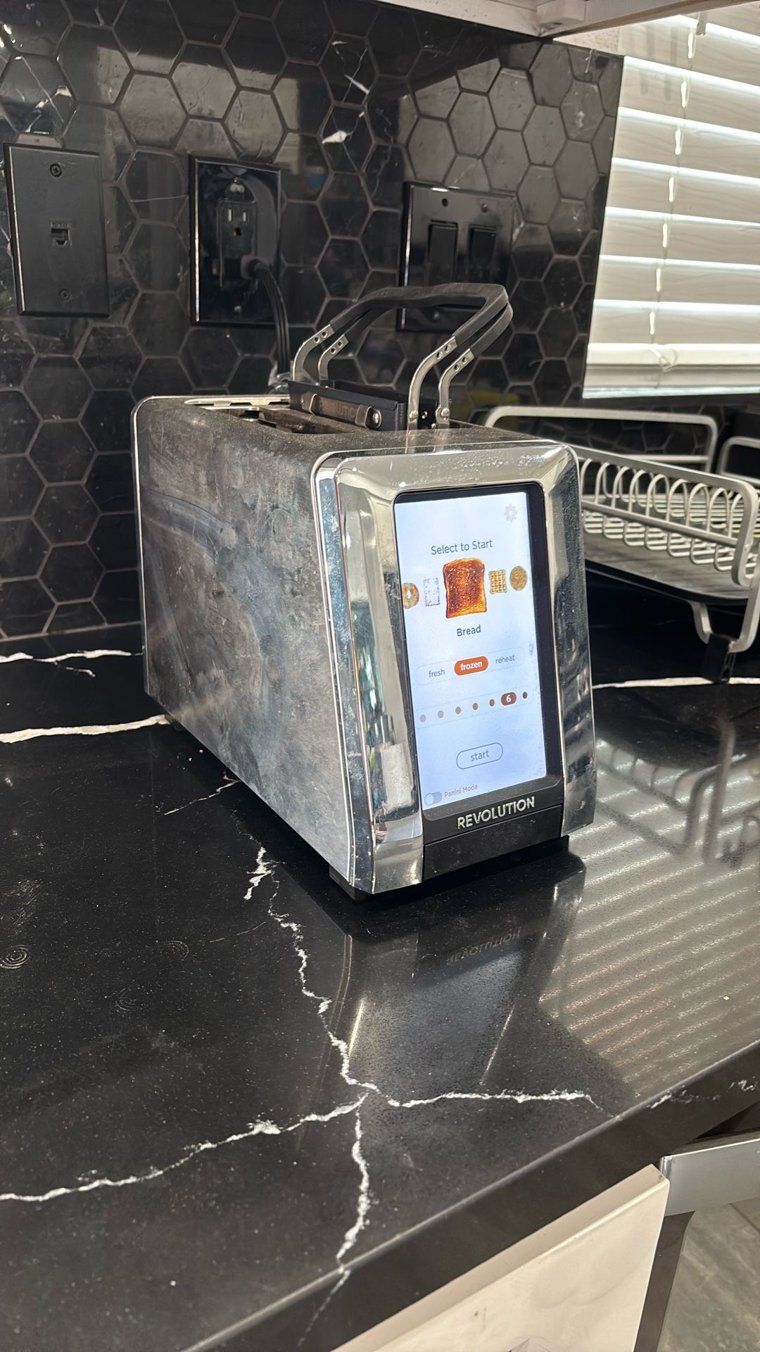 A stainless steel toaster with a large glowing vertical touchscreen on the front