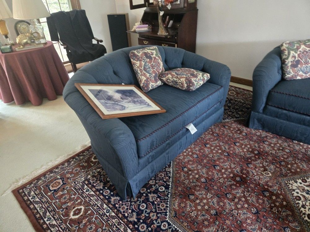 Comfortable blue sofa with two patterned cushions.