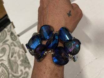 This bracelet features a series of iridescent blue, green, and purple faceted glass beads in varied coin and marquise shapes. The piece is likely vint