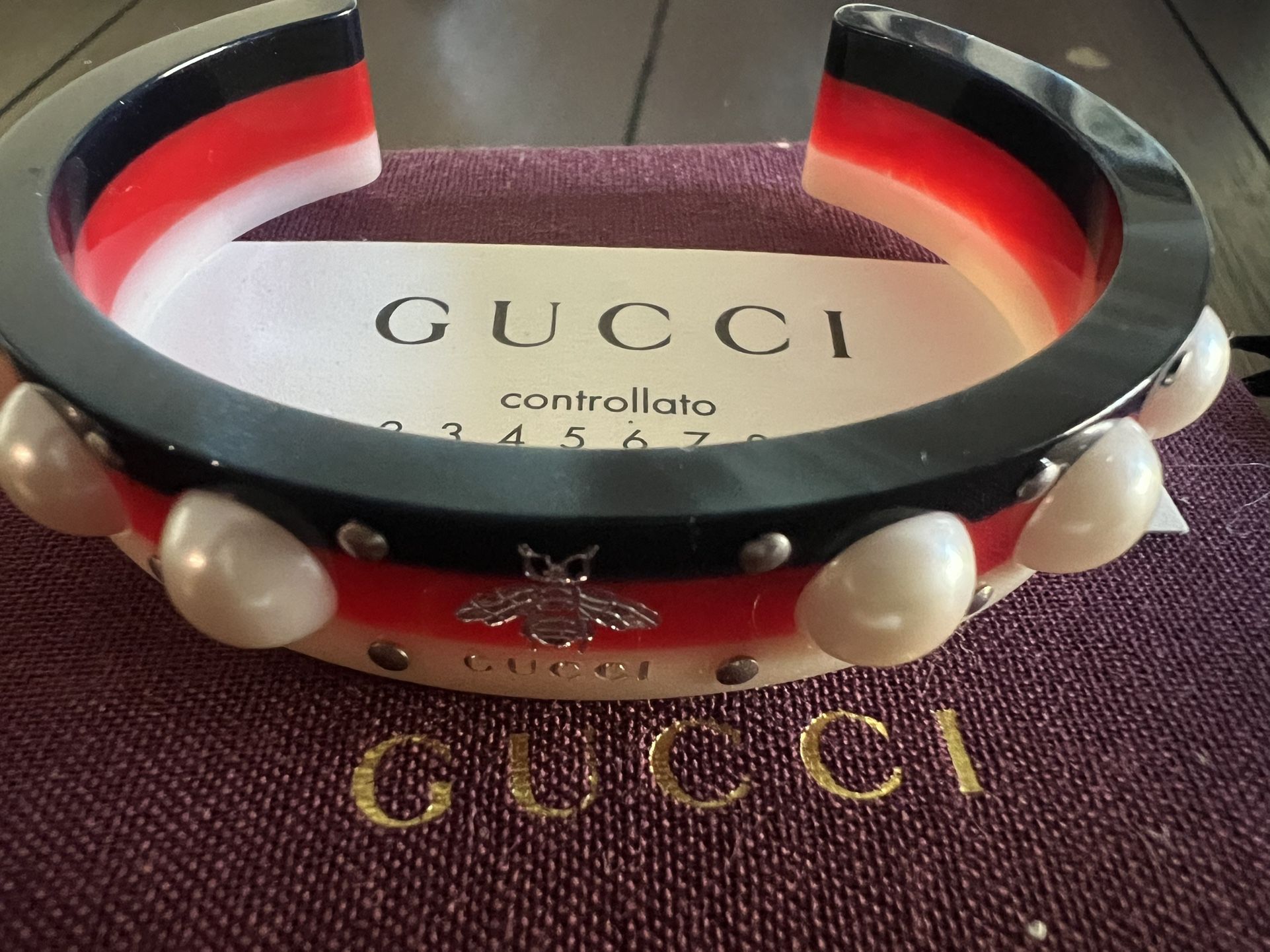 Gucci bracelet with faux pearls, silver-colored rivets and bee motif in white, red and navy blue.