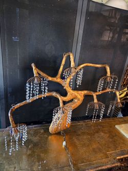 Sculptural chandelier with a gold tree-branch design and crystal drops.