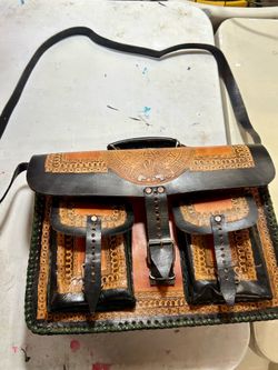 handcrafted leather satchel features a prominent Aztec calendar carving, a style typical of artisanal work from Mexico