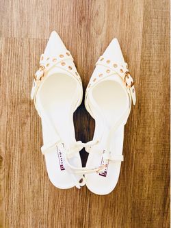 slingback kitten heels featuring a pointed toe, gold-tone buckled straps, and eyelet detailing.