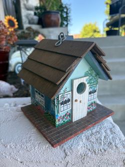 decorative wooden birdhouse featuring hand-painted floral window details and a textured shingled roof.