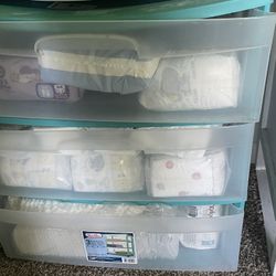 Container stocked with newborn diapers. 11 packs of diapers.