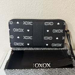 La cartera de la imagen es un modelo de muñequera (wristlet) de la marca XOXO.