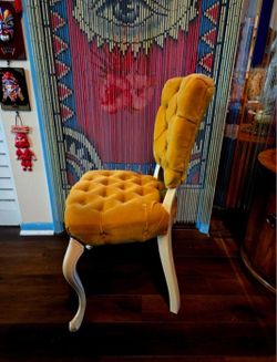 Vintage chair featuring a tufted golden velvet upholstery and a white-painted wooden frame in the Queen Anne or Louis XV style. 