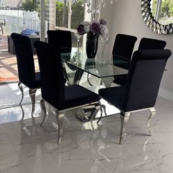 Gorgeous dining table with mirror base and thick glass top. Includes six black velvet and chrome, dining chairs.