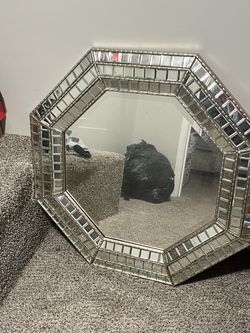 Elegant octagonal wall mirror has a frame constructed from small rectangular mirrored tiles. The piece is made of glass and metal with a silver-toned 
