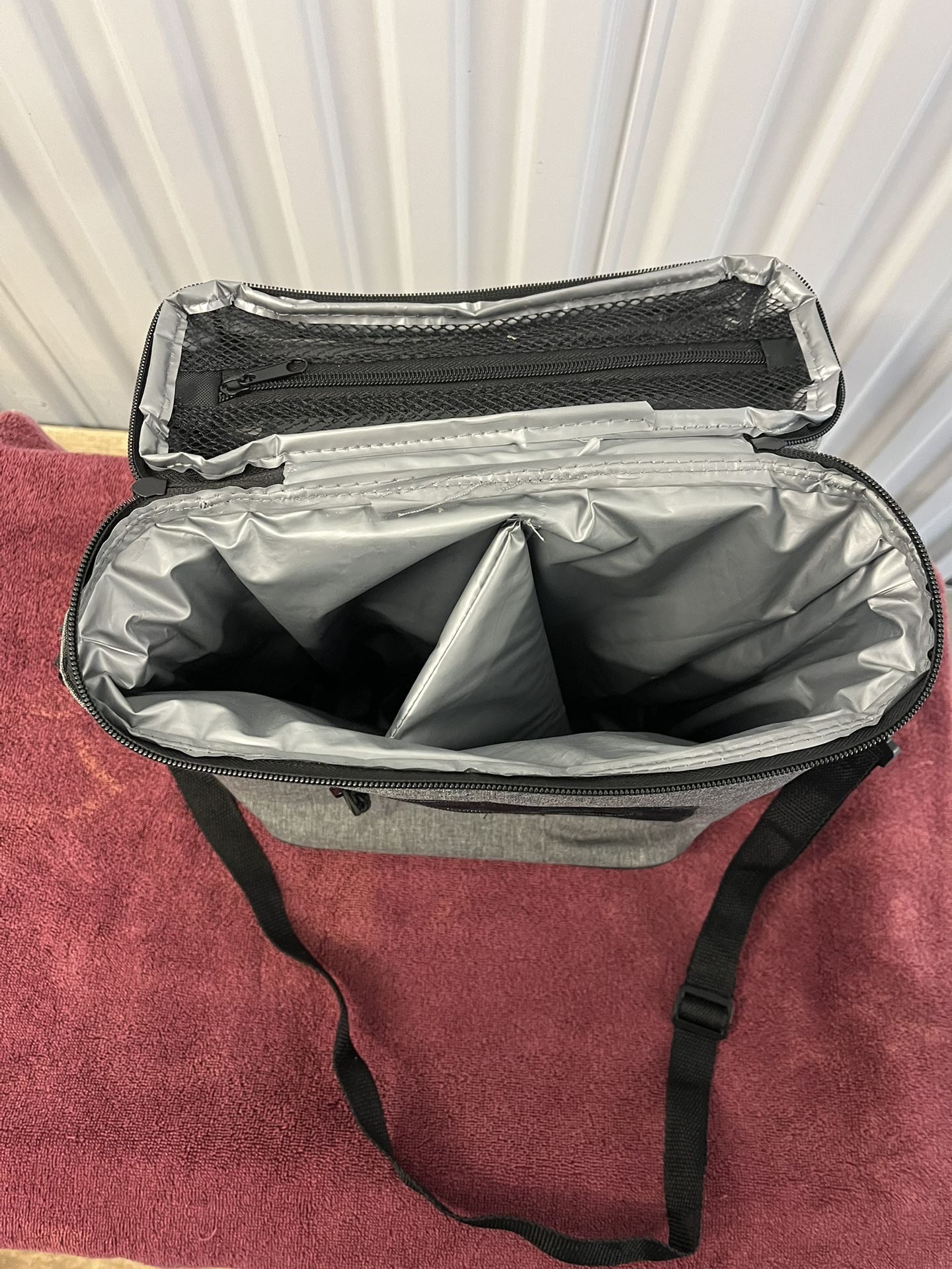 Gray insulated cooler bag with multiple compartments.