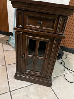 tr dark wood nightstand or small cace t cabinet with one drawer and a glass-door cabinet.