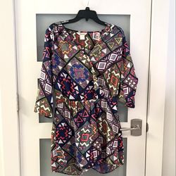 Lucky & Coco romper with a vibrant geometric print. It features a mix of shapes like triangles, diamonds, and multicolored tribal-inspired patterns. S