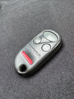 This genuine Honda keyless entry remote key fob features a 4-button layout with Lock, Unlock, Trunk Release, and Panic functions. It is a good replace