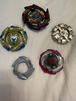 Lot of 5 Beyblade Burst pieces including two fully assembled tops, two metal discs, and one layer. Mix of colors including black/red/gold, green/blue,