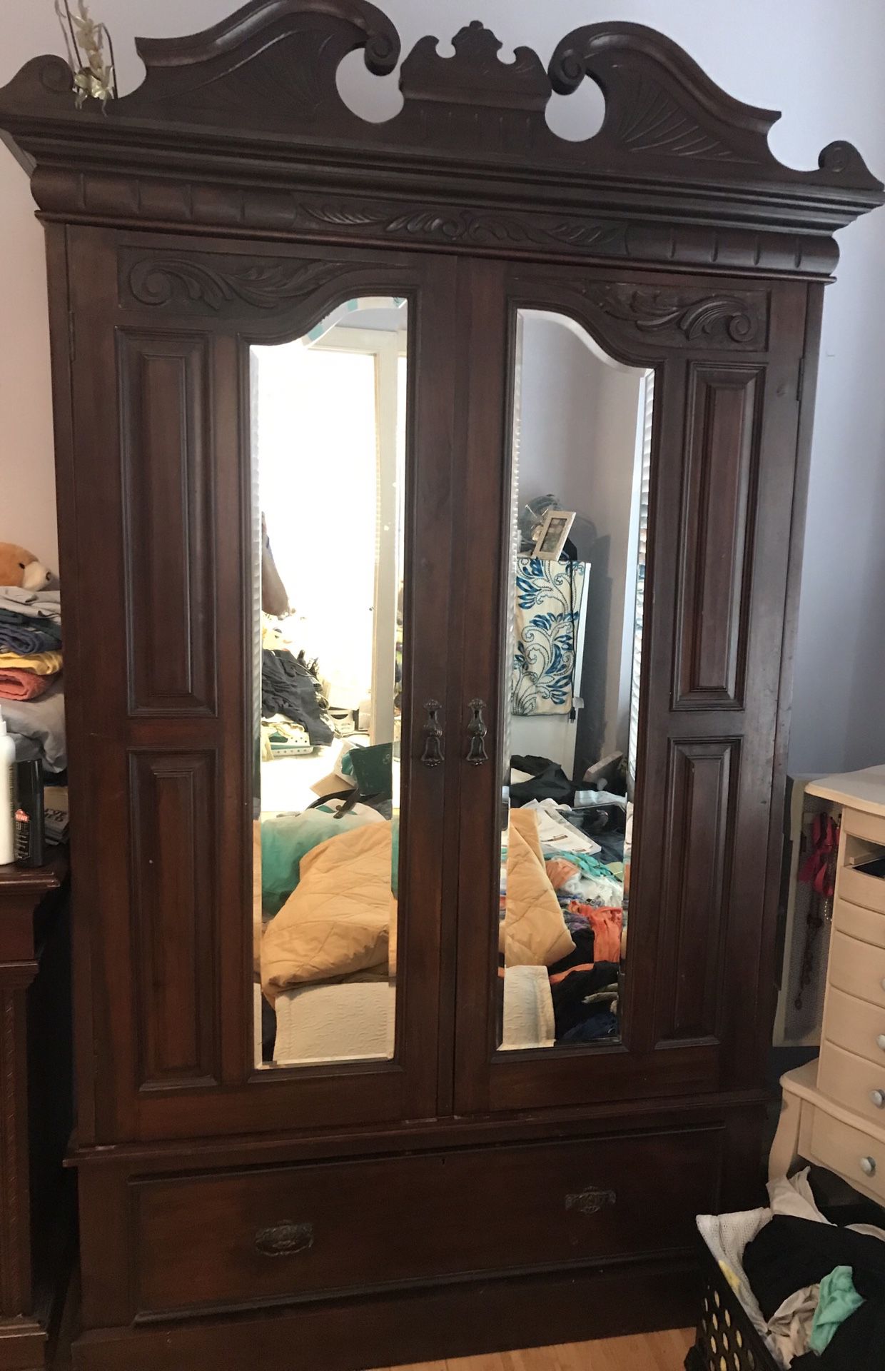 Antique dark mahogany wood armoire with beveled glass doors and low, wide drawer. Top decorative crown removes for transportation.