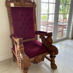 2 large, hand-carved mahogany throne chairs with a high back and red velvet upholstery