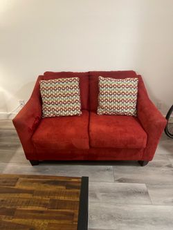 Red microfiber loveseat in excellent condition with two matching accent pillows included.