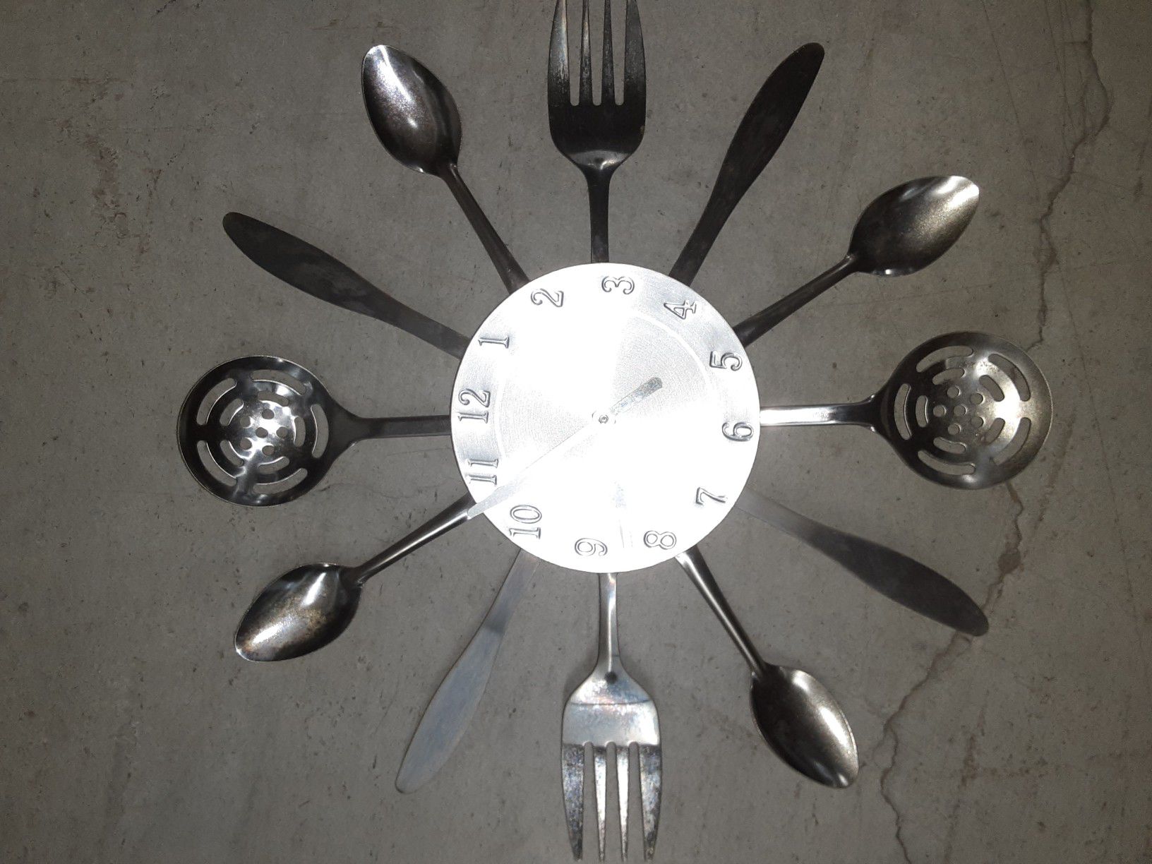 A household clock made out of silver kitchen utensils