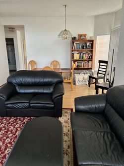 Classic black leather sofa set featuring plush, rounded rolled arms and segmented back cushions
