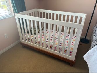 White crib with medium wood base/legs.