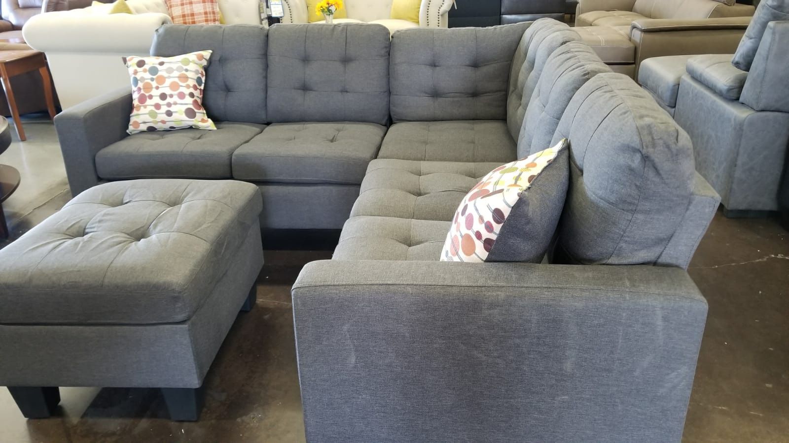 A small bluish grey sectional with a matching ottoman