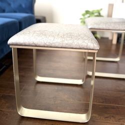 2 sets of small gray faux leather vanity ottoman with gold metal legs.