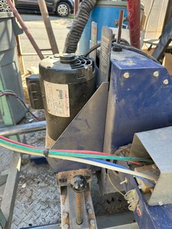 Industrial-grade pneumatic machine is powered by a black electric motor and features a blue metal housing. This unit has a foot-operated pneumatic ped
