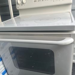 white electric glass-top range from GE with 5 burners (including warming zone) and a digital oven