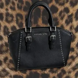 The Michael Kors Ciara Grommet Medium Messenger Satchel is a stylish Saffiano leather bag featuring eyelet pattern detailing, grommet accents, and a d