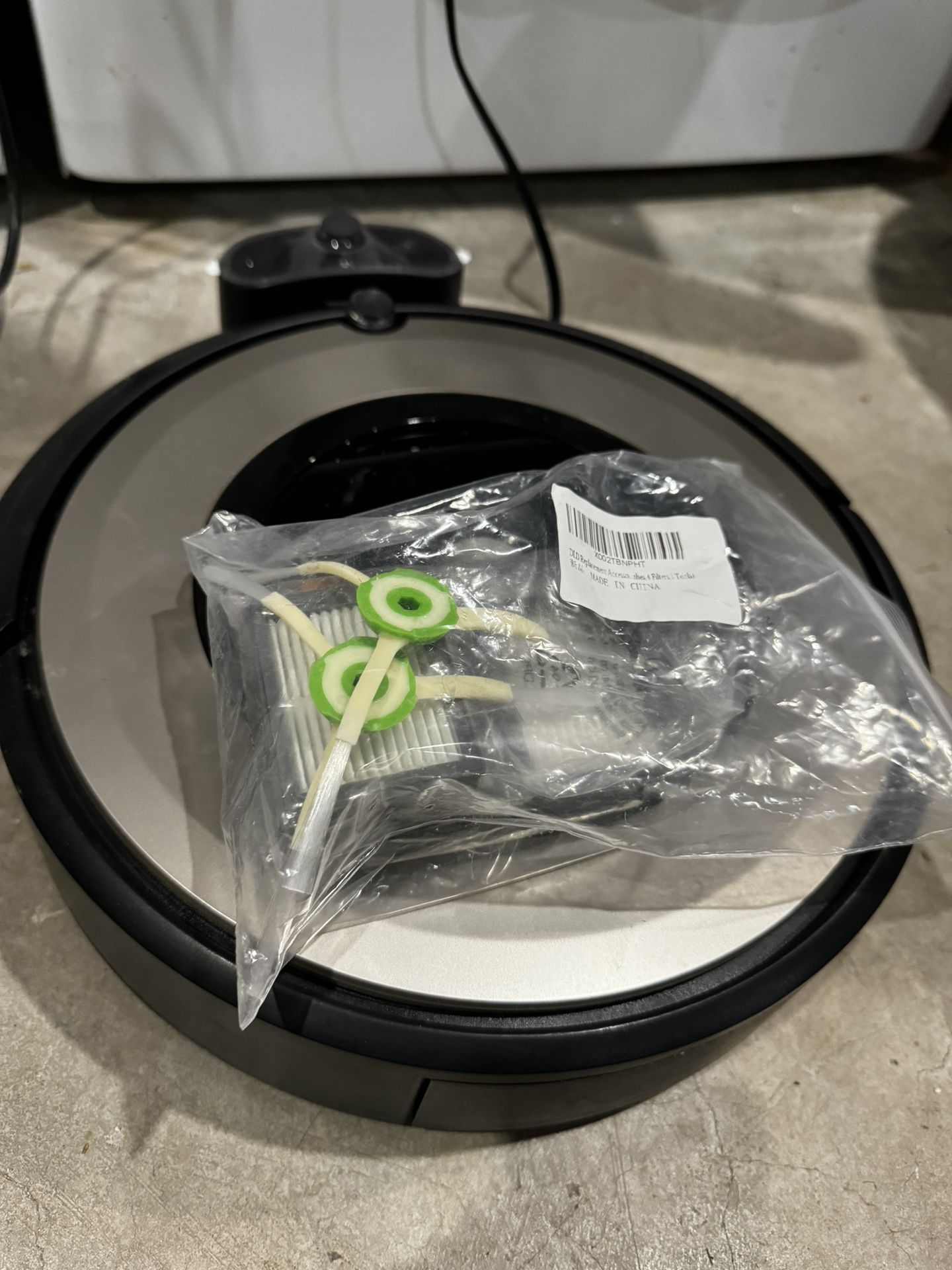 Roomba with spare filters and parts.