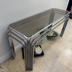 1970s vintage chrome and smoked glass console table, often featuring a waterfall design