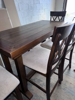 “Rustic counter-height dining table with upholstered X-back chairs.”