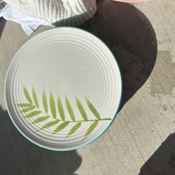 This is a Home Ipanema dinner plate with a palm leaf design and turquoise rim