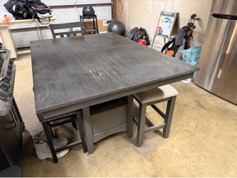 Gray counter-height dining table with a chair and a bench.