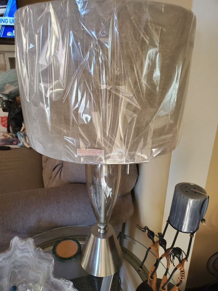 Beautiful glass and metal silver base lamp With beige shade still in plastic.