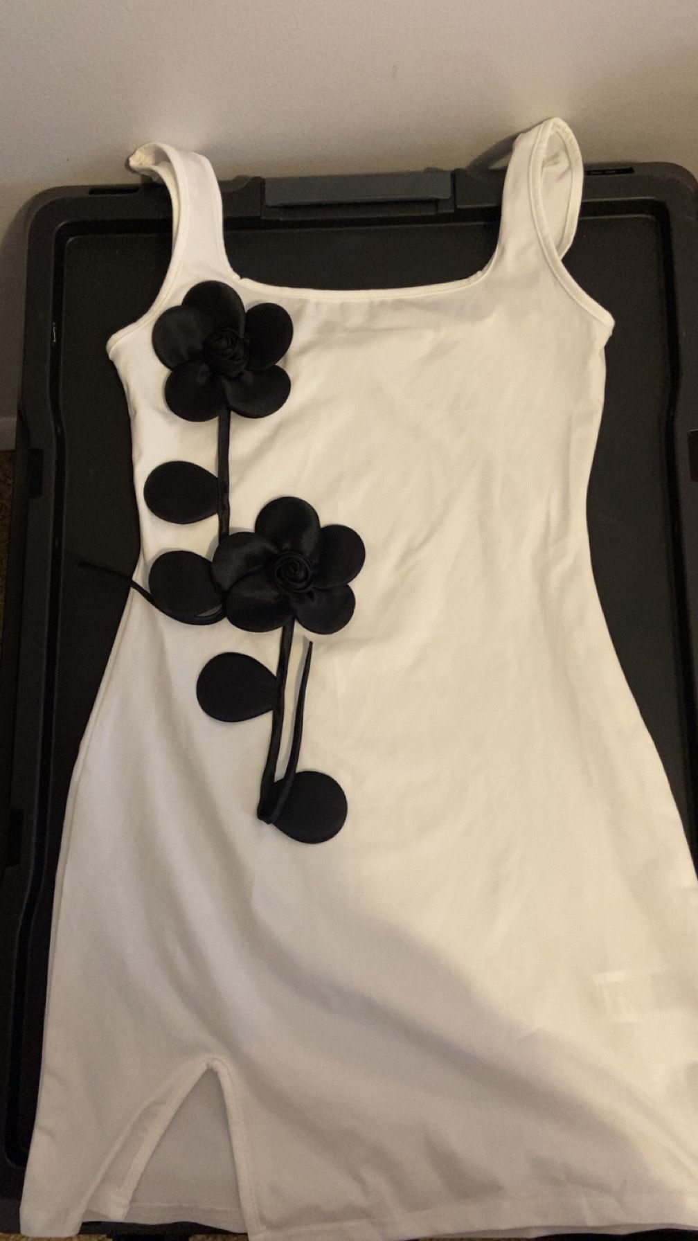 white mini dress featuring black 3D floral appliqué decorations and a hem slit
