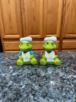 Ceramic Pair of Green dinosaurs dressed up as a Chef Pair of Salt & Pepper Shakers. Size 3 inches tall.  Brand new never used.  Some minor paint wear 