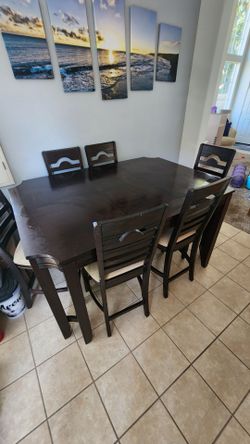 Bar height dining table with 6 upholstered chairs.