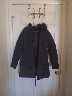 This image shows a dark navy blue Nautica women's puffer coat featuring a plush faux-fur trimmed hood and quilted design