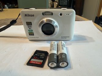 Waterproof white Nikon Coolpix S30 digital camera has a Nikkor 3x optical zoom lens. This camera is shockproof and includes a 32GB SanDisk Extreme PRO