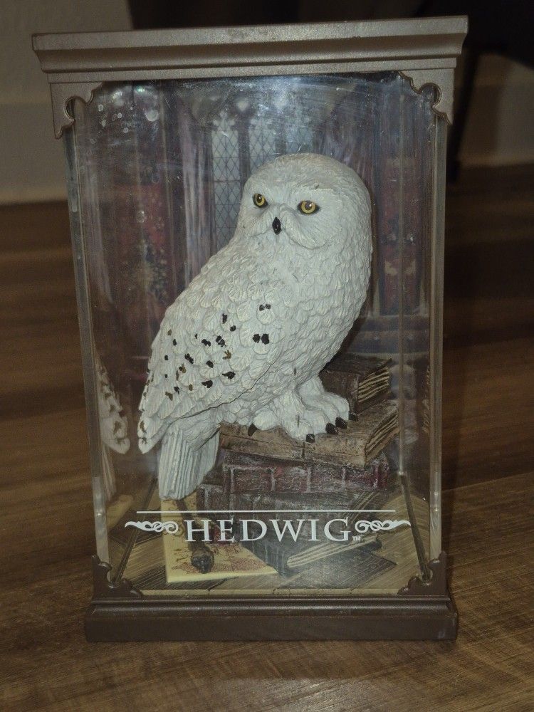 Display of Hedwig perched on a stack of books next to the Marauder's Map and Harry Potter's Wand