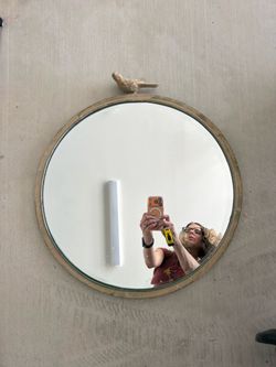 Round antiqued metal frame beveled mirror with bird perched on top