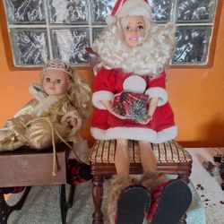 2 Dolls. 1 Barbie And Other Doll, Dress As Santa  Sitting In Wood Chair And Bench.