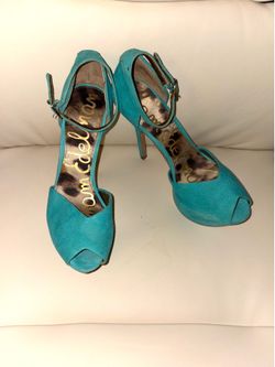 These heels are the Marina model by Sam Edelman, distinguished by their vibrant turquoise color, prominent platform, and high stiletto heel. They feat
