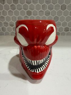 Bold red ceramic decorative piece inspired by a venomous character. Glossy red finish with striking white eyes and black-and-white tooth detail. Eye-c