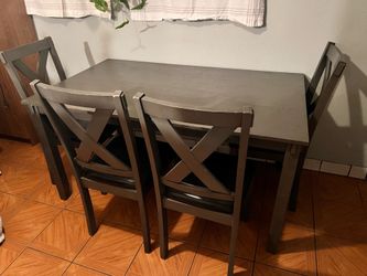 This is a contemporary dining table set featuring a dark gray finish and X-back chairs with black upholstered seats